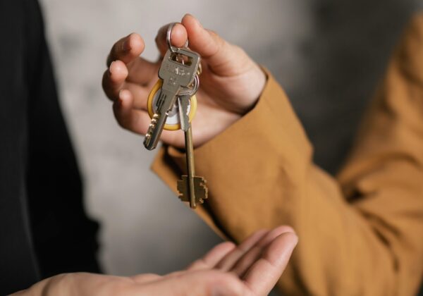 Two adults exchanging house keys, symbolic of property transfer or rental agreement.